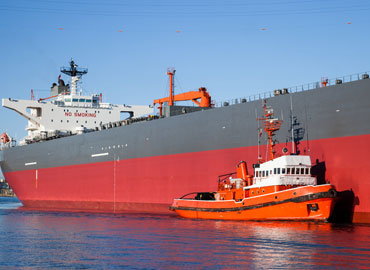 A tugboat assisting tanker near port